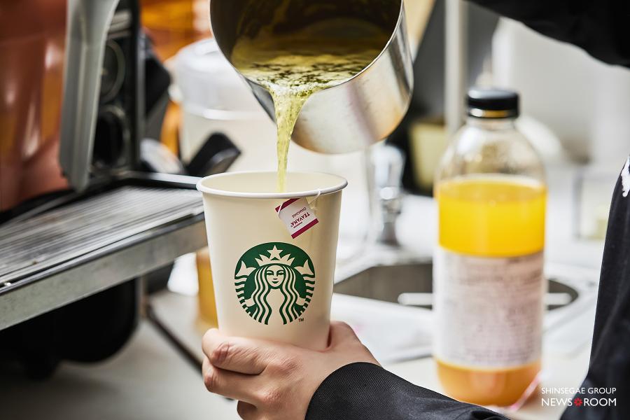 스타벅스 매장에서 파트너가 컵에 차 음료를 정성스럽게 제조하여 따르고 있는 모습